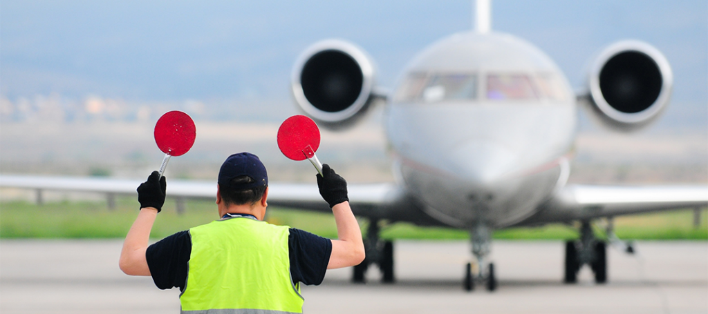 Ein Dispatcher weist ein Flugzeug auf seine Parkposition ein.