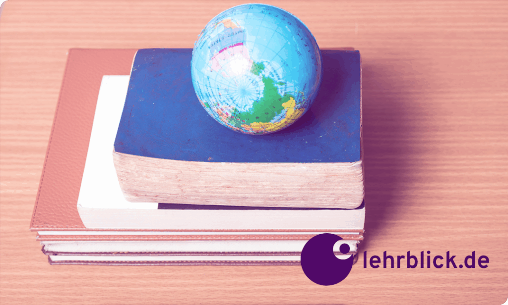 Bücherstapel auf einer Tischplatte, oben liegt ein Globus