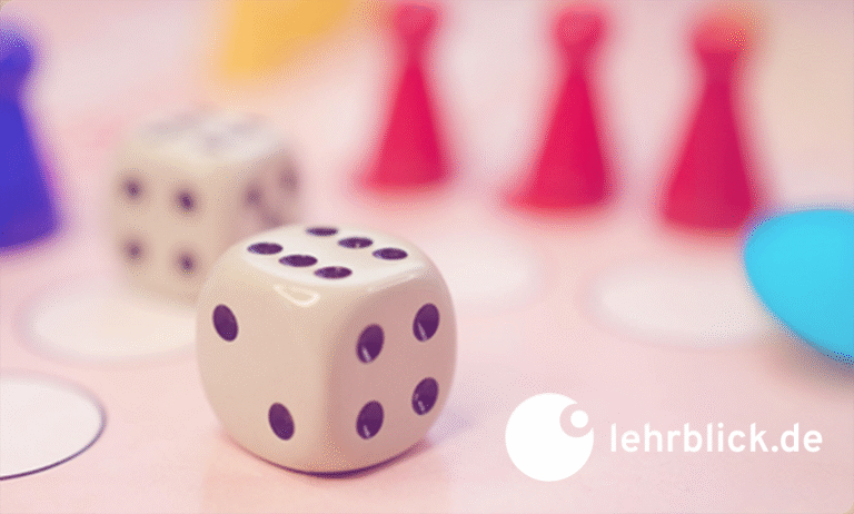 Nahaufnahme eines weißen Würfels mit schwarzen Punkten auf einem Spielbrett, im Hintergrund rote Spielfiguren und ein weiterer Würfel, unten rechts das Logo von lehrblick.de