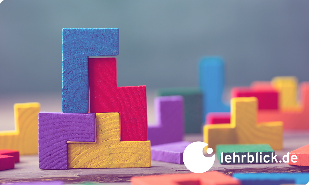 Bunte Holzbausteine in verschiedenen Formen, die ineinandergreifen und einen Turm bilden.