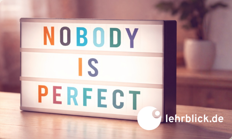Leuchtkasten mit den Worten 'NOBODY IS PERFECT' in bunten Großbuchstaben auf einem Tisch