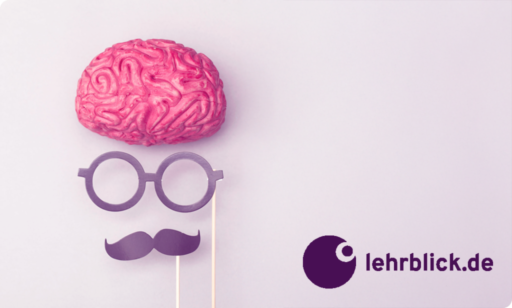 Modell eines rosa Gehirns über einer Brille und einem Schnurrbart aus Papier an Stäben vor hellem Hintergrund mit Logo und Schriftzug 'lehrblick.de'