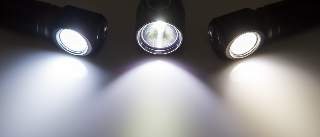 Drei Deckenstrahler mit eingeschaltetem Licht, die Lichtkegel auf eine weiße Fläche werfen