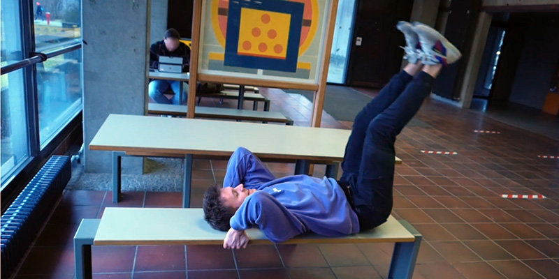 Ein Student macht auf einer Bank eine Bauchmuskelübung